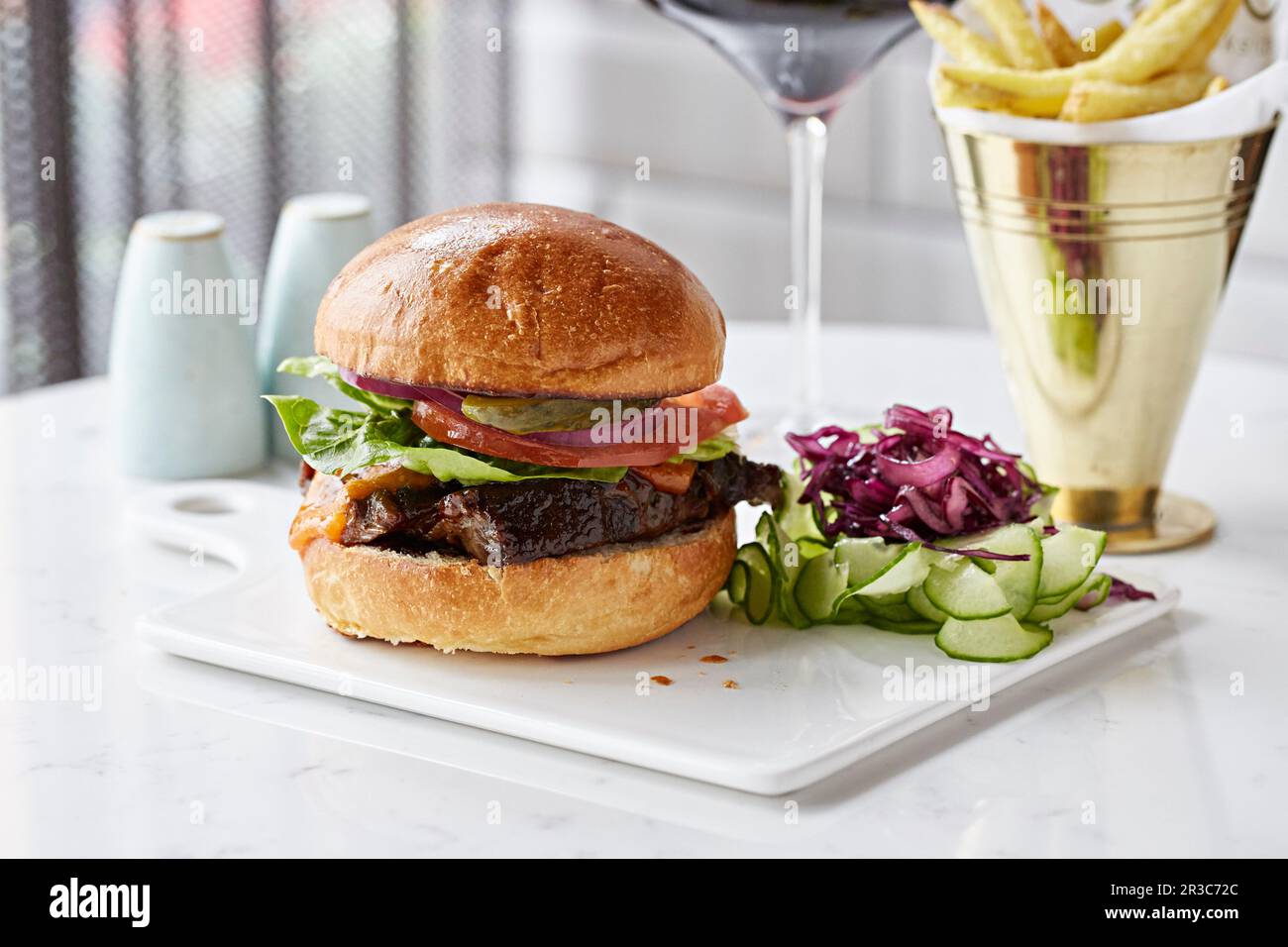 Hamburger di bistecca con cetriolo sottaceto, cavolo viola e patatine fritte Foto Stock