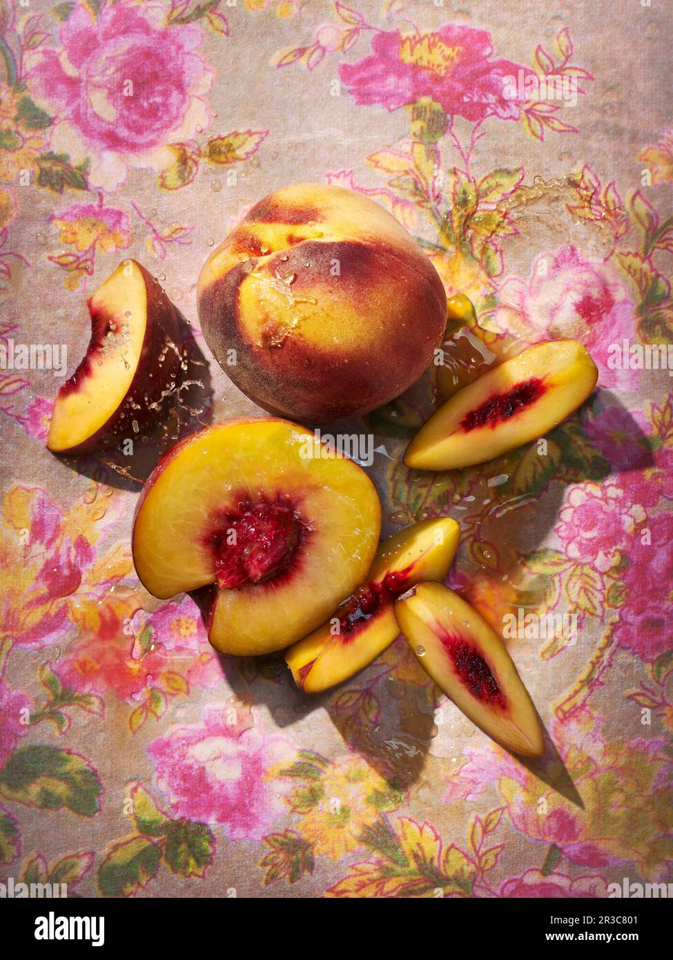 Pesche fresche, intere e tagliate su fondo floreale Foto Stock