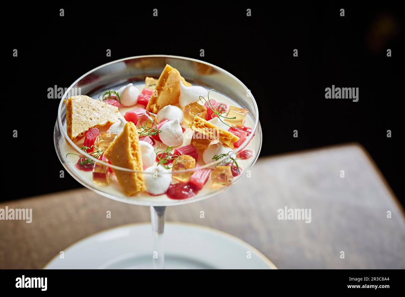 Dessert al rabarbaro con nido d'ape e meringa in un bicchiere a gambo Foto Stock