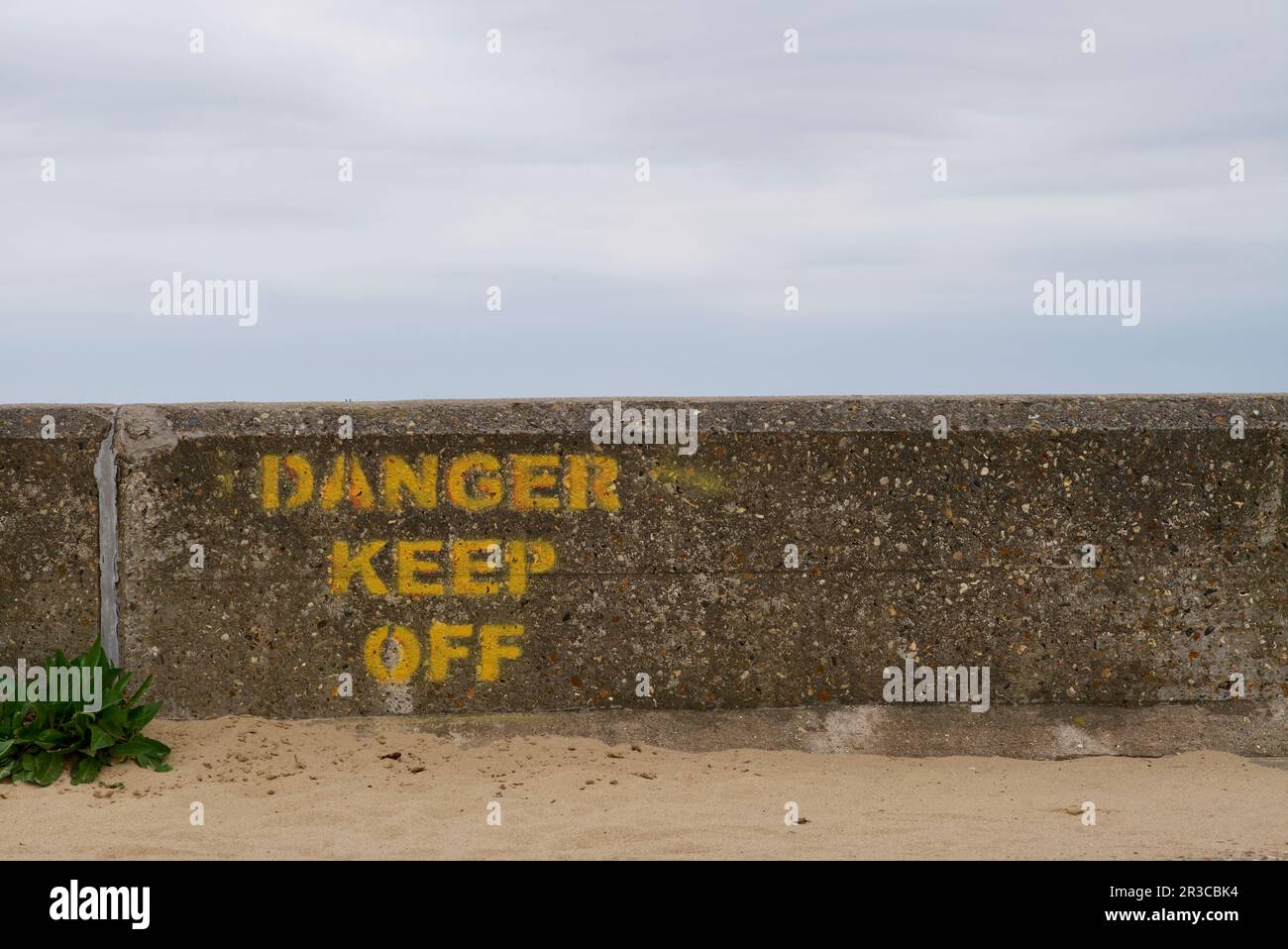 Parete del mare con cartello di avvertimento dipinto sulla parete. Foto Stock