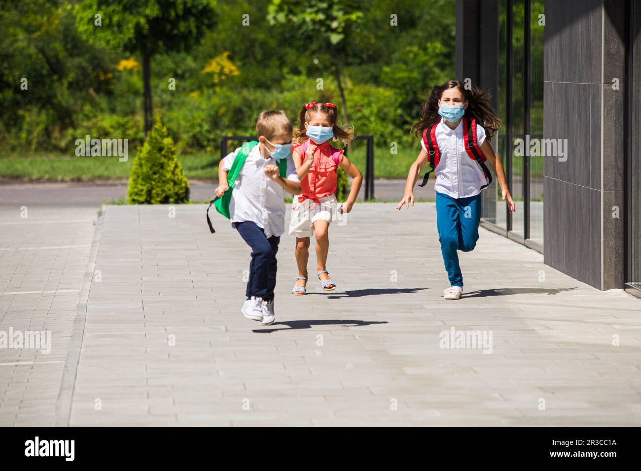 I bambini felici corrono a scuola in una pandemia Foto Stock