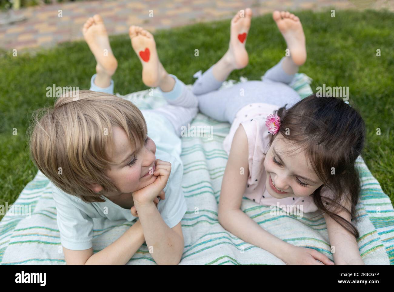 due bambini allegri, un ragazzo e una ragazza, sdraiati sull'erba verde Foto Stock