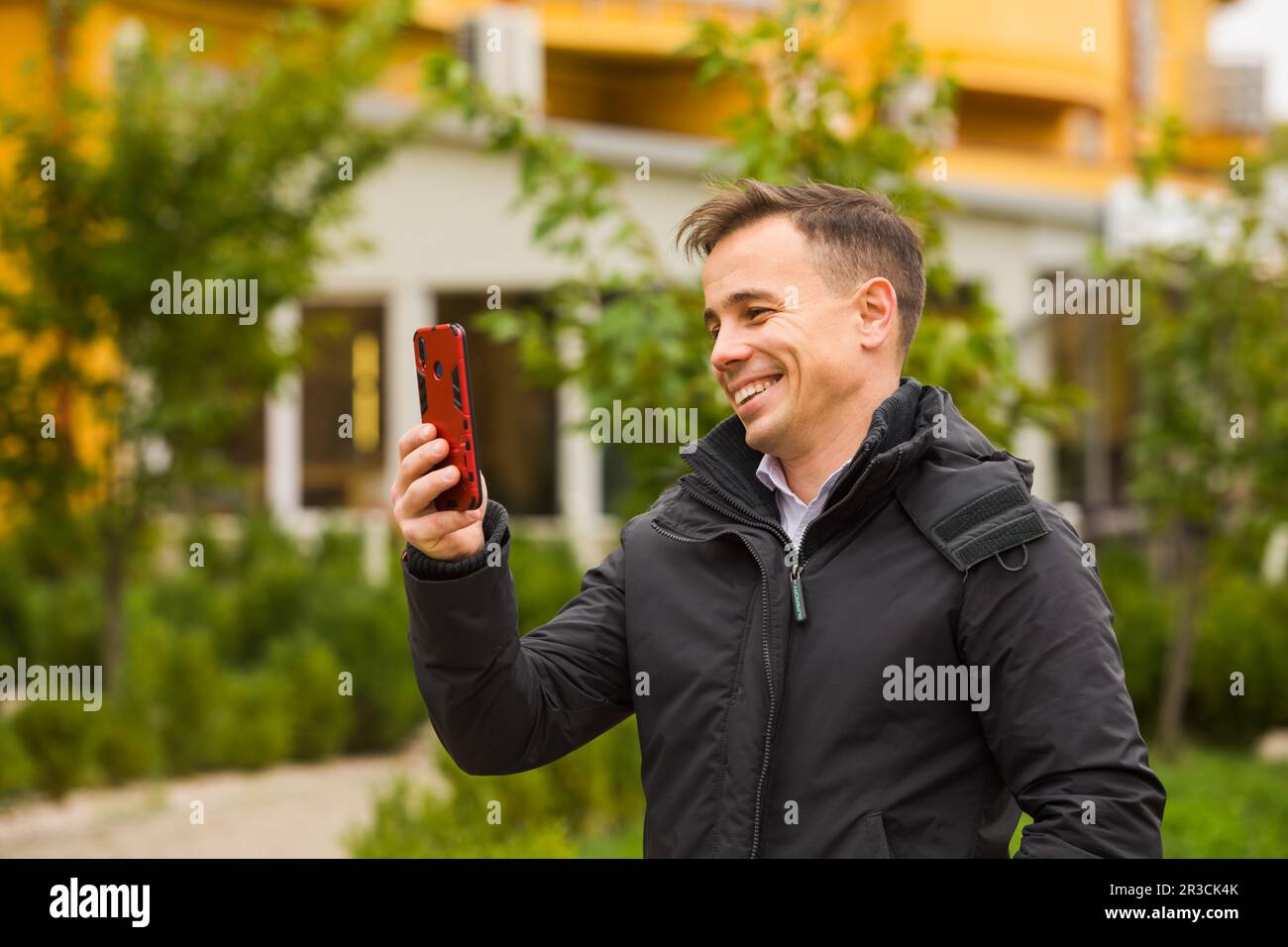 L'uomo felice sta tenendo il telefono ed avendo videochat all'aperto Foto Stock