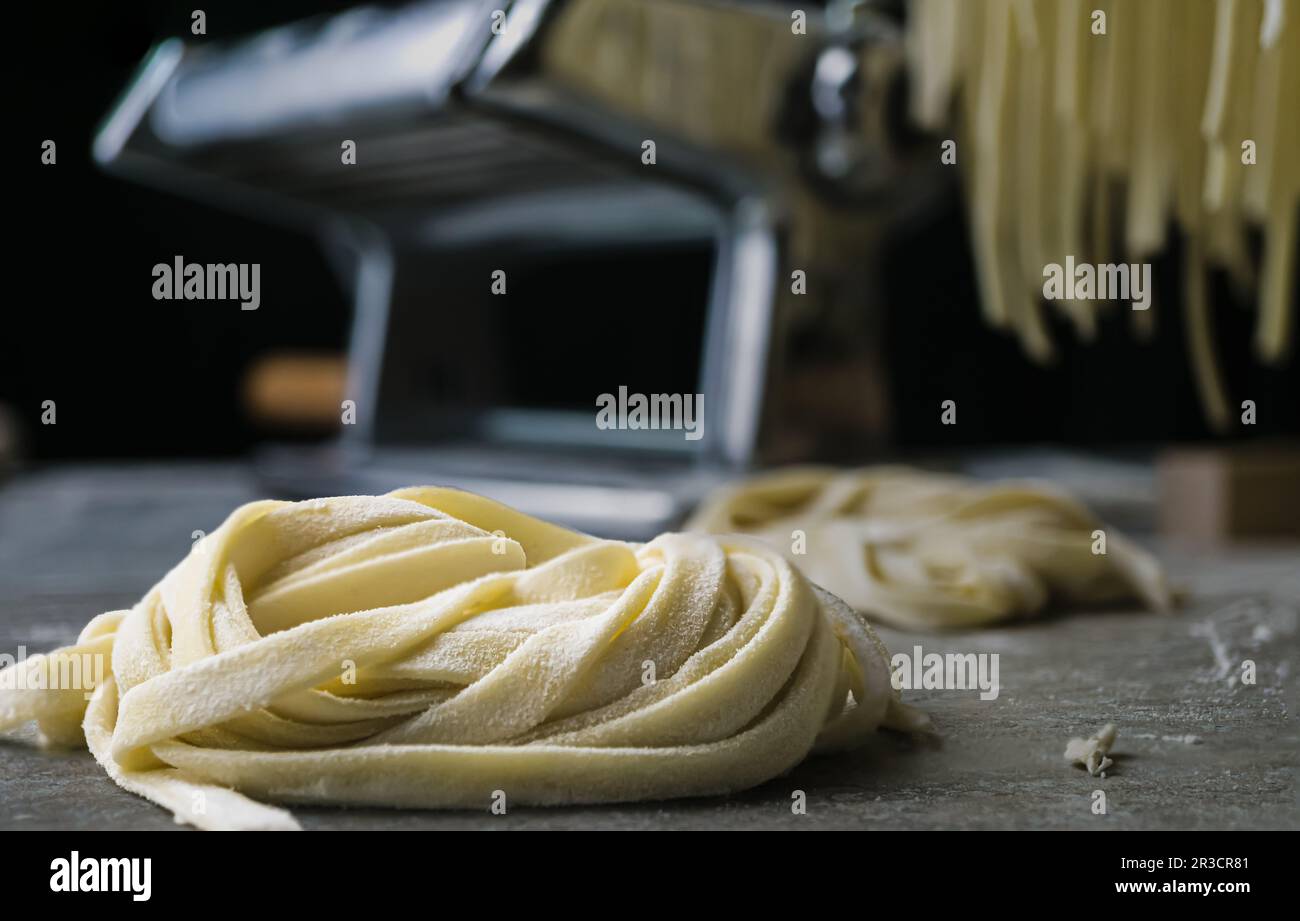 Fettuccine fresche asciugate su una rastrelliera di legno. Primo piano. Foto Stock