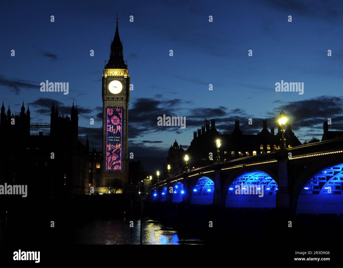 Elizabeth Tower con esposizione luminosa che celebra l'incoronazione di Re Carlo III con il Westminster Bridge sulla destra, Londra, Regno Unito. Foto Stock