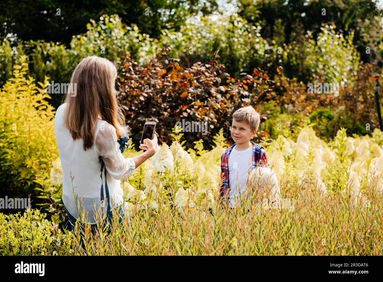 Madre insegna al figlio di camminare in giardino Foto Stock