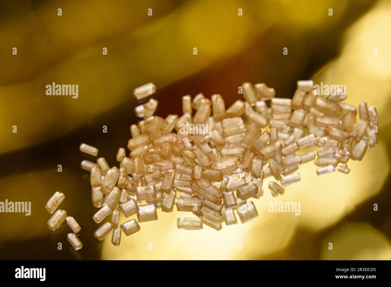 cristalli di zucchero di canna su vetro trasparente e fondo con effetto bokeh Foto Stock