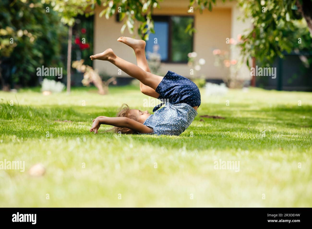 La bambina attiva fa un somersault sul cortile Foto Stock