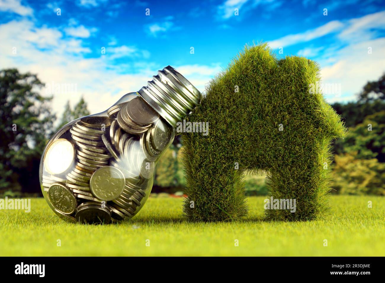 Monete all'interno della lampadina e casa in miniatura con erba. Eco-verde energia rinnovabile concetto. I prezzi dell'elettricità, il risparmio energetico in famiglia. Foto Stock
