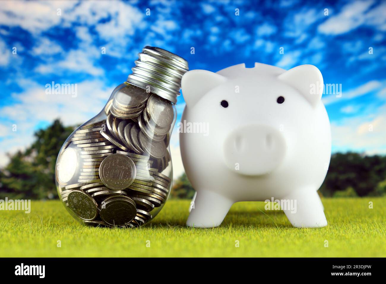 Monete all'interno della lampadina e del banco di porcellini. Eco-verde energia rinnovabile concetto. I prezzi dell'elettricità, il risparmio energetico in famiglia. Foto Stock