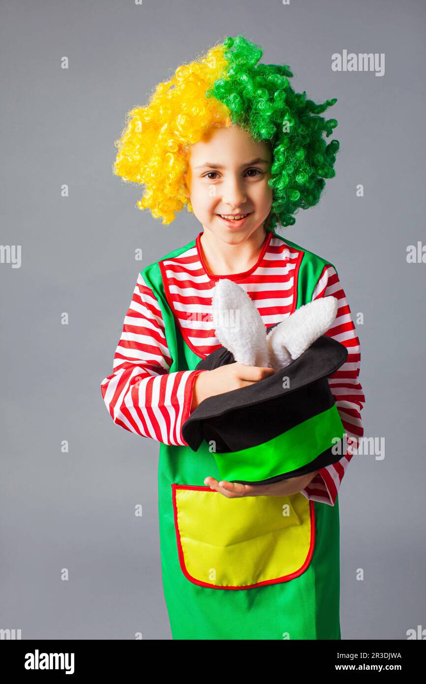 La bambina in un costume di clown dimostra trucco con un coniglietto Foto Stock