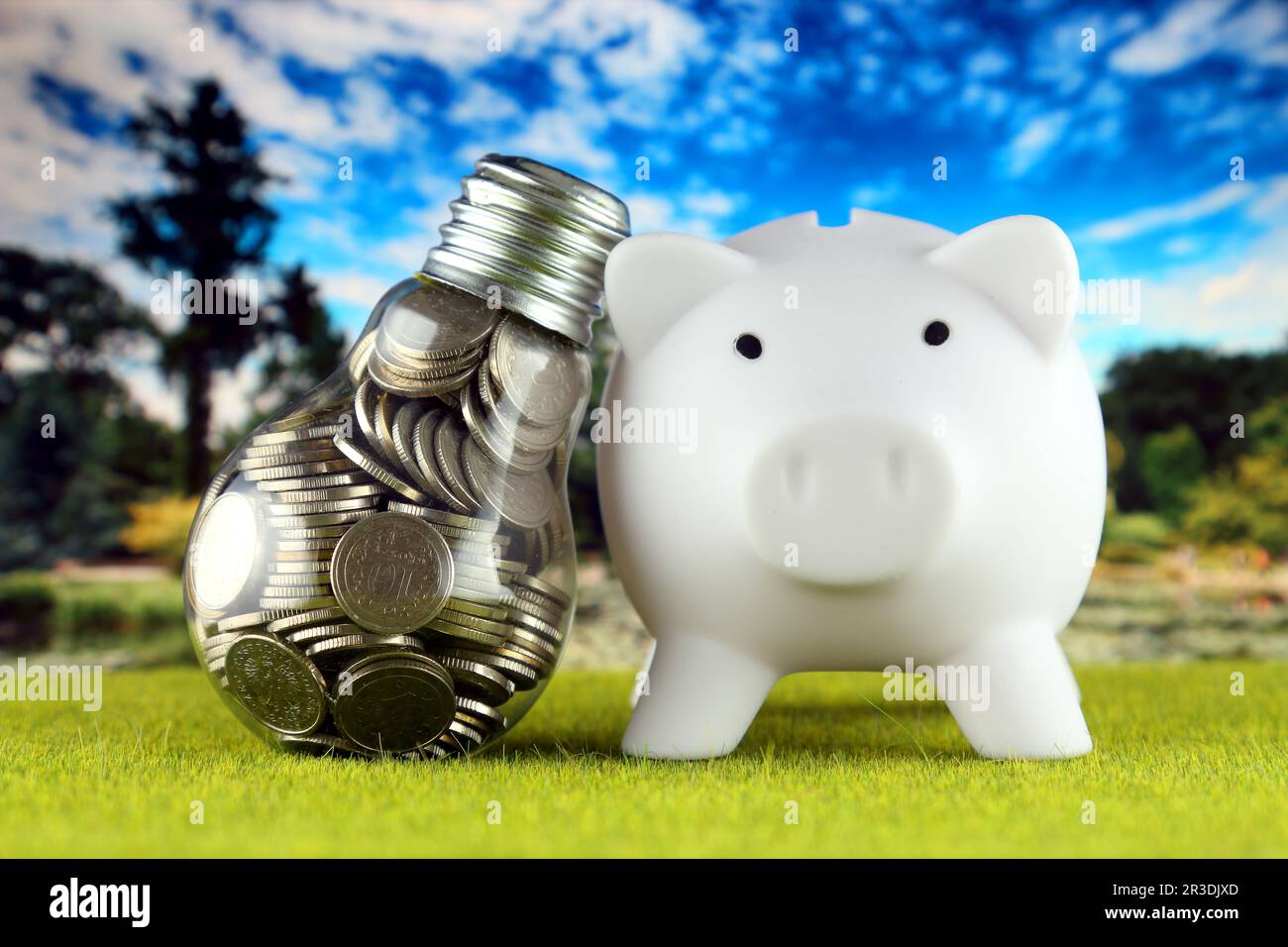 Monete all'interno della lampadina e del banco di porcellini. Eco-verde energia rinnovabile concetto. I prezzi dell'elettricità, il risparmio energetico in famiglia. Foto Stock