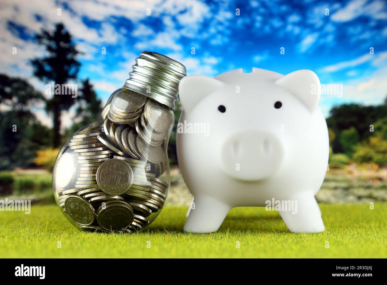 Monete all'interno della lampadina e del banco di porcellini. Eco-verde energia rinnovabile concetto. I prezzi dell'elettricità, il risparmio energetico in famiglia. Foto Stock