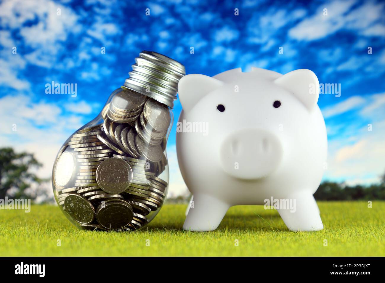 Monete all'interno della lampadina e del banco di porcellini. Eco-verde energia rinnovabile concetto. I prezzi dell'elettricità, il risparmio energetico in famiglia. Foto Stock