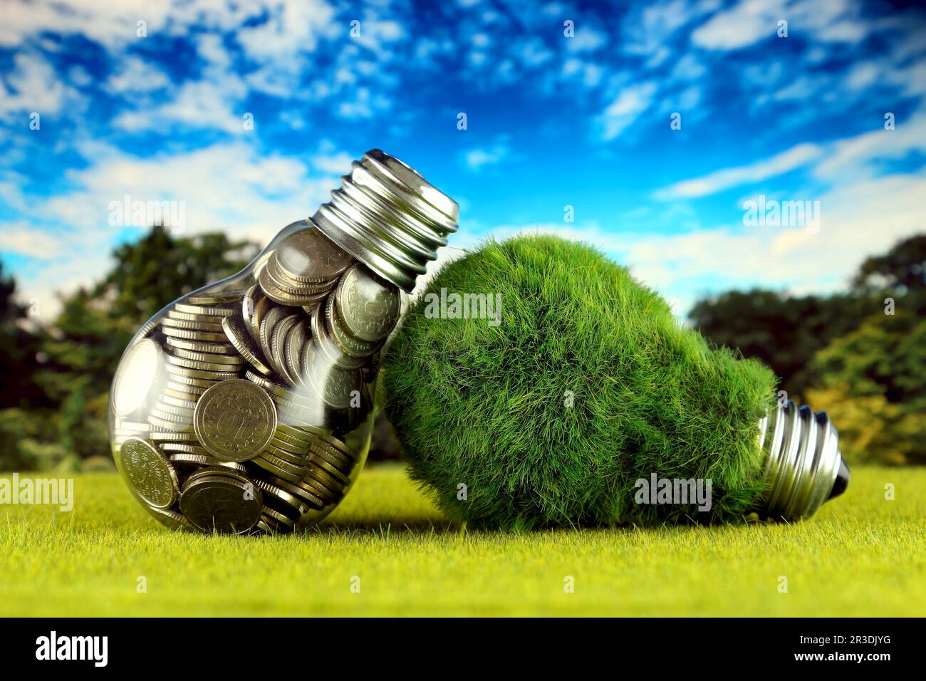 Monete all'interno della lampadina e lampadina verde eco con erba. Concetto di energia rinnovabile. I prezzi dell'elettricità, il risparmio energetico in famiglia. Foto Stock