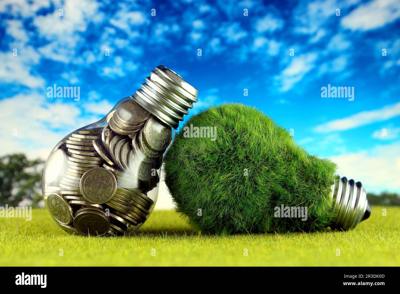 Monete all'interno della lampadina e lampadina verde eco con erba. Concetto di energia rinnovabile. I prezzi dell'elettricità, il risparmio energetico in famiglia. Foto Stock