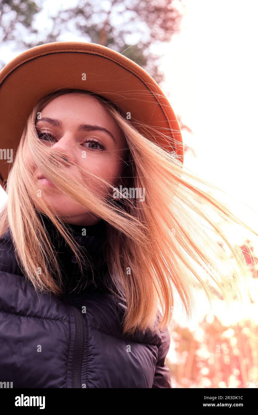 Ritratto di giovane donna con capelli biondi in cappello. Vento all'esterno. Selfie Foto Stock