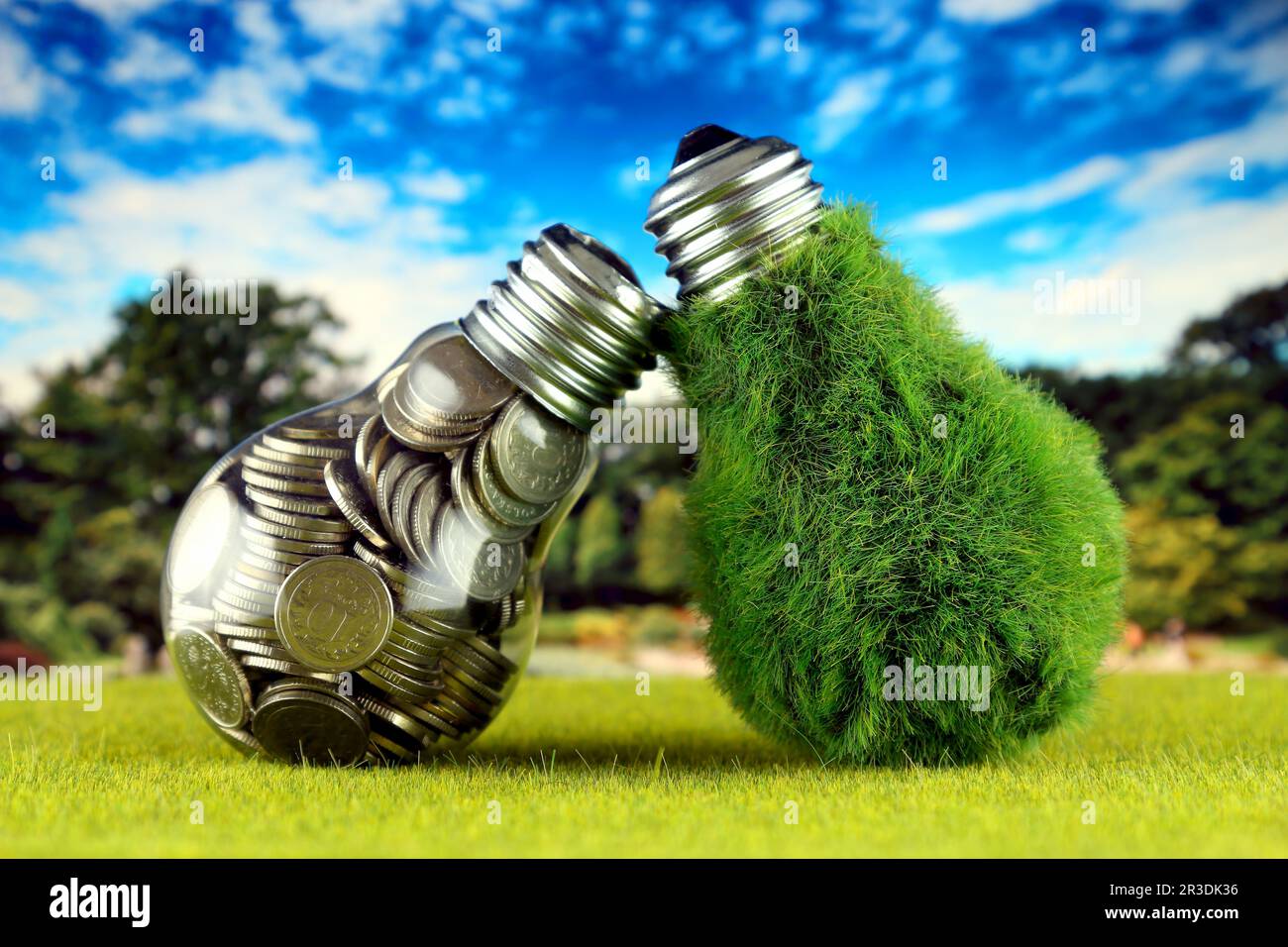 Monete all'interno della lampadina e lampadina verde eco con erba. Concetto di energia rinnovabile. I prezzi dell'elettricità, il risparmio energetico in famiglia. Foto Stock