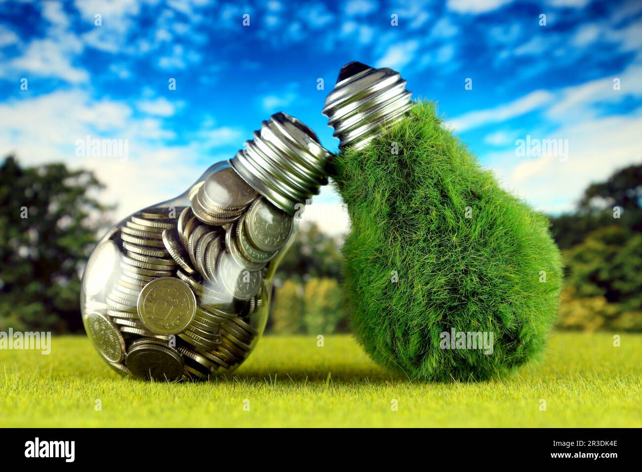 Monete all'interno della lampadina e lampadina verde eco con erba. Concetto di energia rinnovabile. I prezzi dell'elettricità, il risparmio energetico in famiglia. Foto Stock