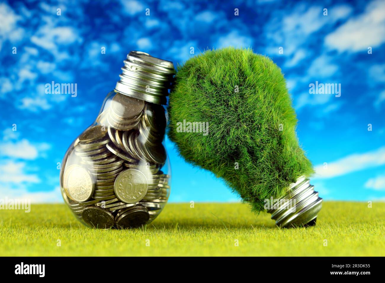 Monete all'interno della lampadina e lampadina verde eco con erba. Concetto di energia rinnovabile. I prezzi dell'elettricità, il risparmio energetico in famiglia. Foto Stock