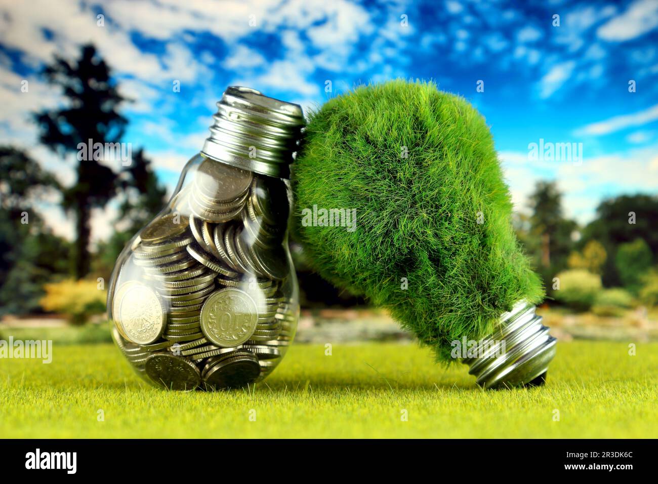 Monete all'interno della lampadina e lampadina verde eco con erba. Concetto di energia rinnovabile. I prezzi dell'elettricità, il risparmio energetico in famiglia. Foto Stock