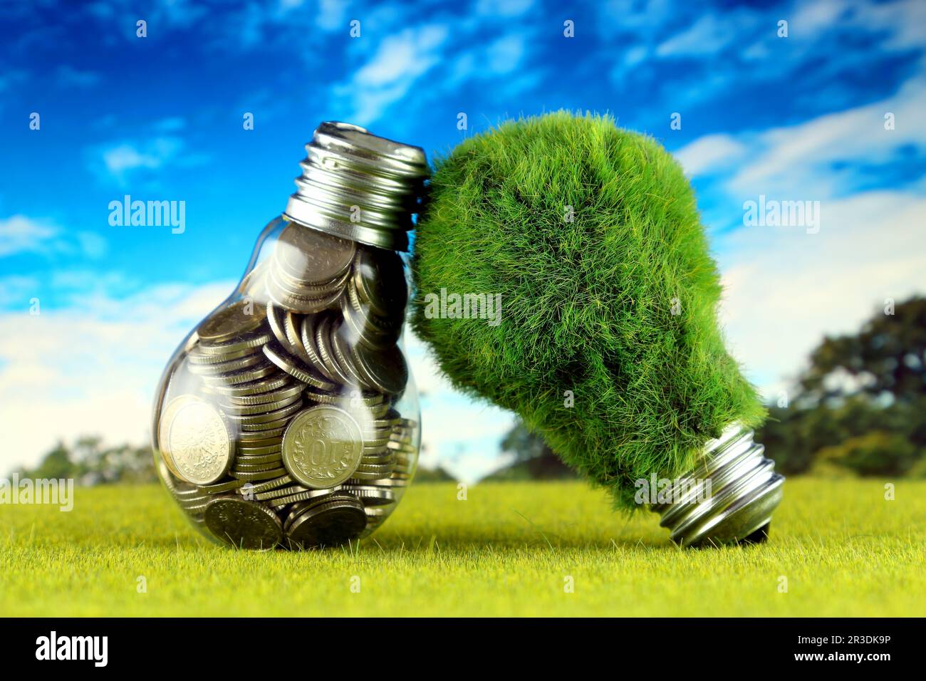 Monete all'interno della lampadina e lampadina verde eco con erba. Concetto di energia rinnovabile. I prezzi dell'elettricità, il risparmio energetico in famiglia. Foto Stock