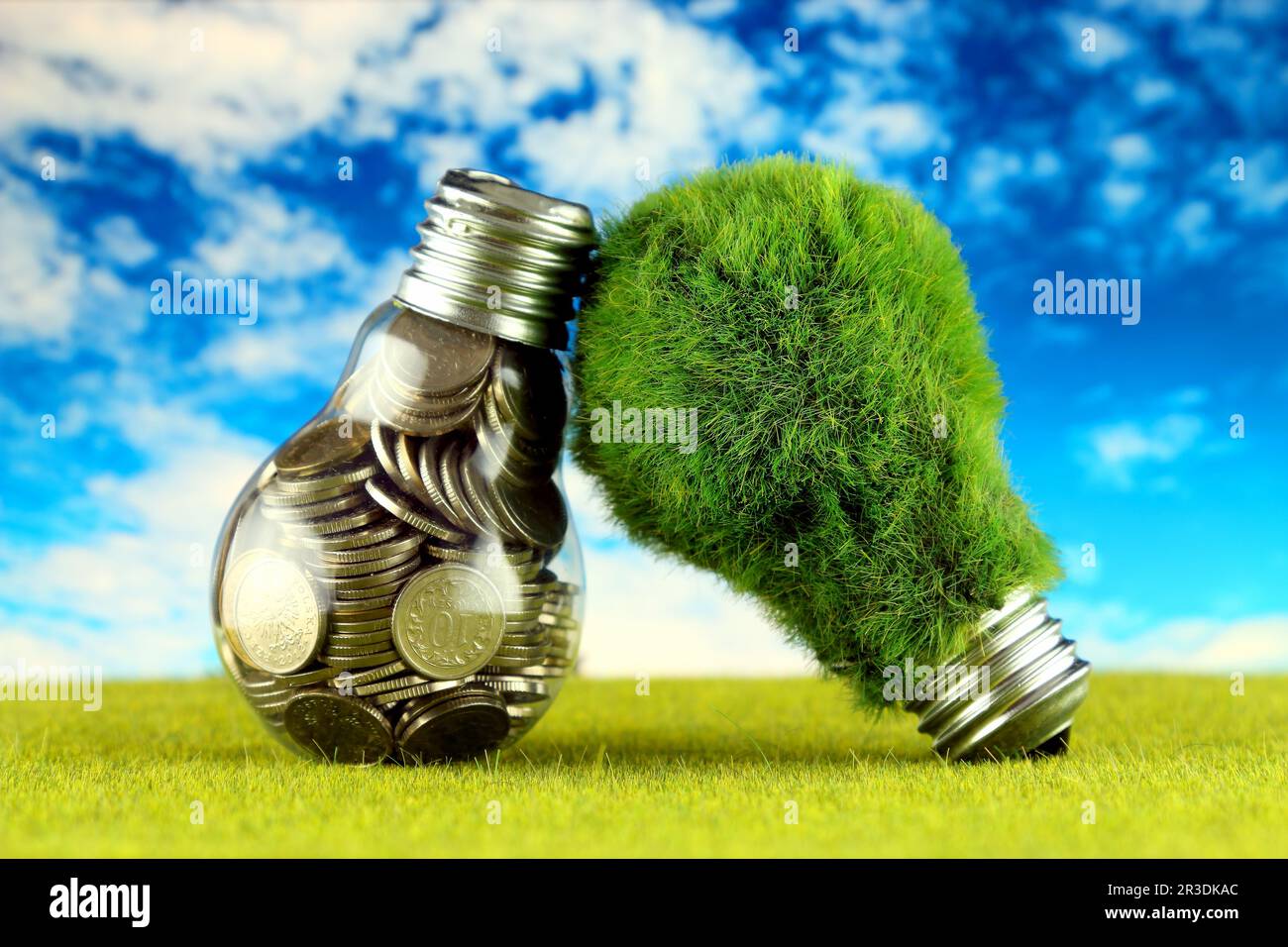 Monete all'interno della lampadina e lampadina verde eco con erba. Concetto di energia rinnovabile. I prezzi dell'elettricità, il risparmio energetico in famiglia. Foto Stock