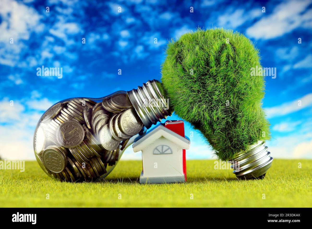 Monete all'interno della lampadina, lampadina verde eco con erba e casa in miniatura. Concetto di energia rinnovabile. I prezzi dell'elettricità, il risparmio energetico nelle ore Foto Stock