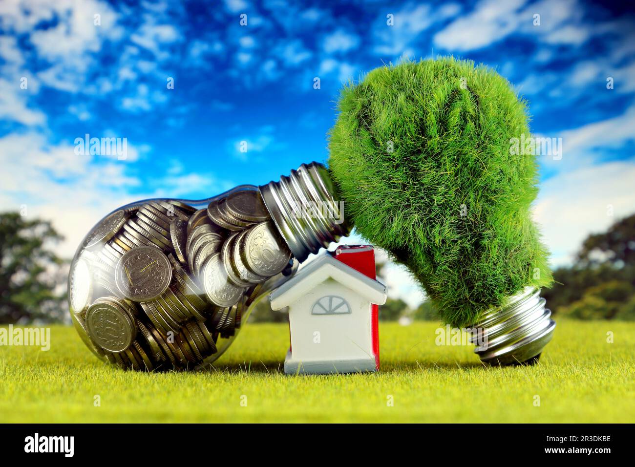 Monete all'interno della lampadina, lampadina verde eco con erba e casa in miniatura. Concetto di energia rinnovabile. I prezzi dell'elettricità, il risparmio energetico nelle ore Foto Stock