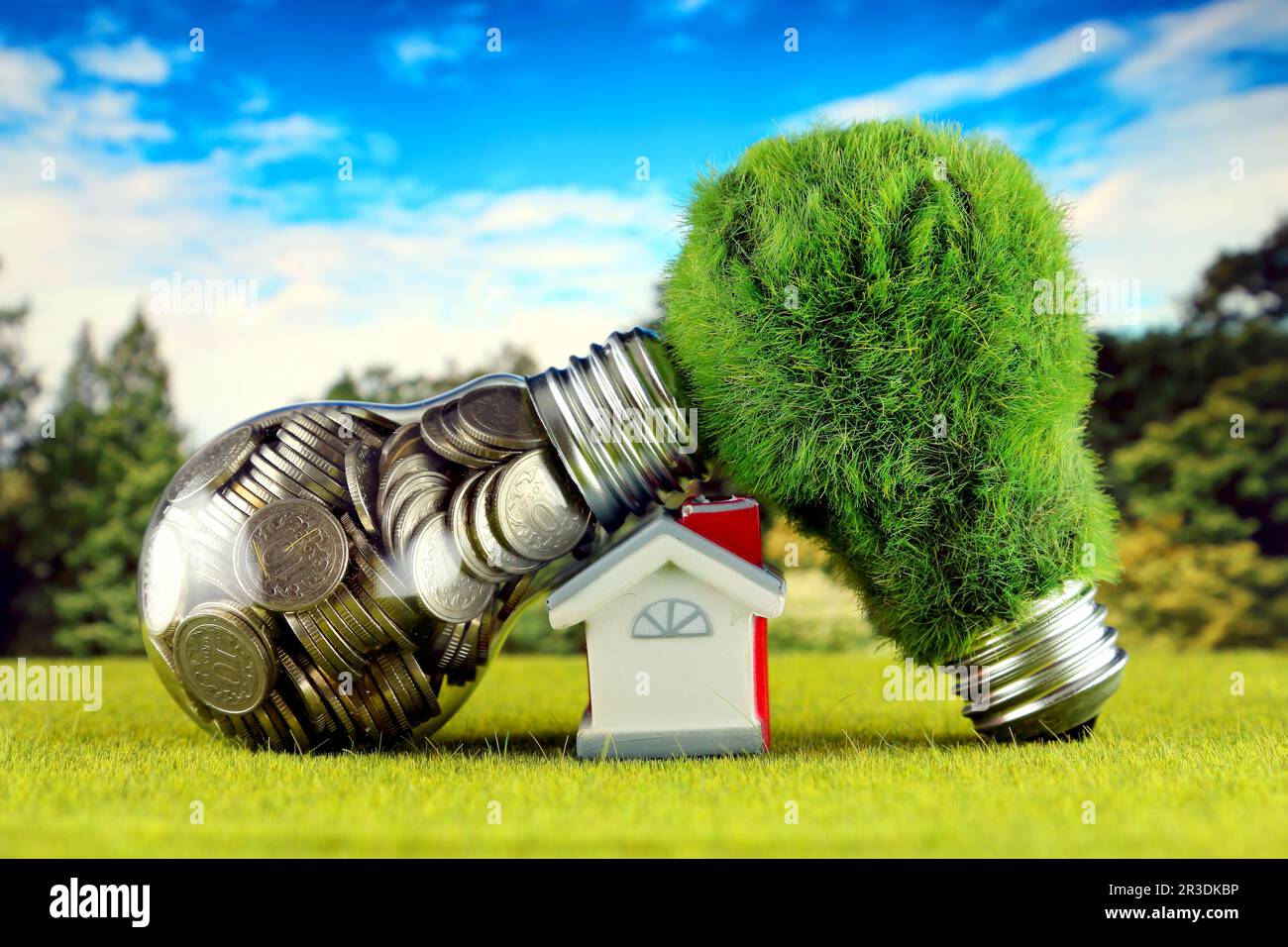 Monete all'interno della lampadina, lampadina verde eco con erba e casa in miniatura. Concetto di energia rinnovabile. I prezzi dell'elettricità, il risparmio energetico nelle ore Foto Stock