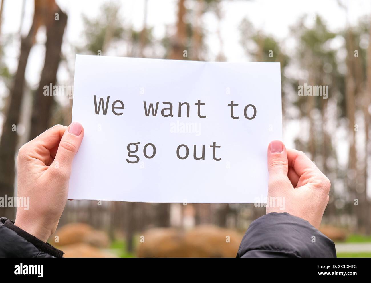 Le mani femminili tengono il foglio bianco di carta con il testo che vogliamo uscire all'aperto. Natura sfondo. Attivista protettore Foto Stock