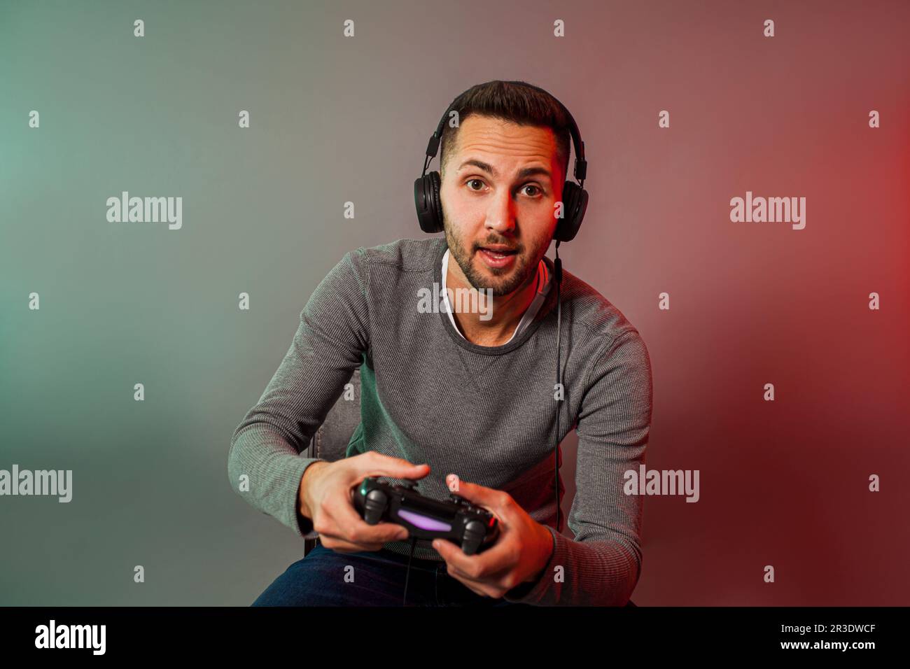 Uomo che tiene il joystick e gioca al gioco virtuale Foto Stock