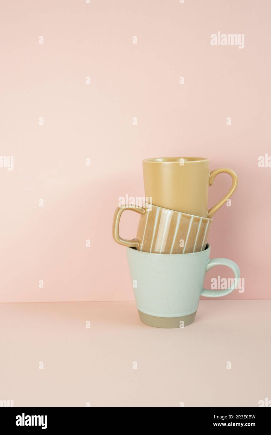 Pila di tazze di tazza marrone e blu menta sul tavolo rosa. sfondo parete rosa. spazio di copia Foto Stock
