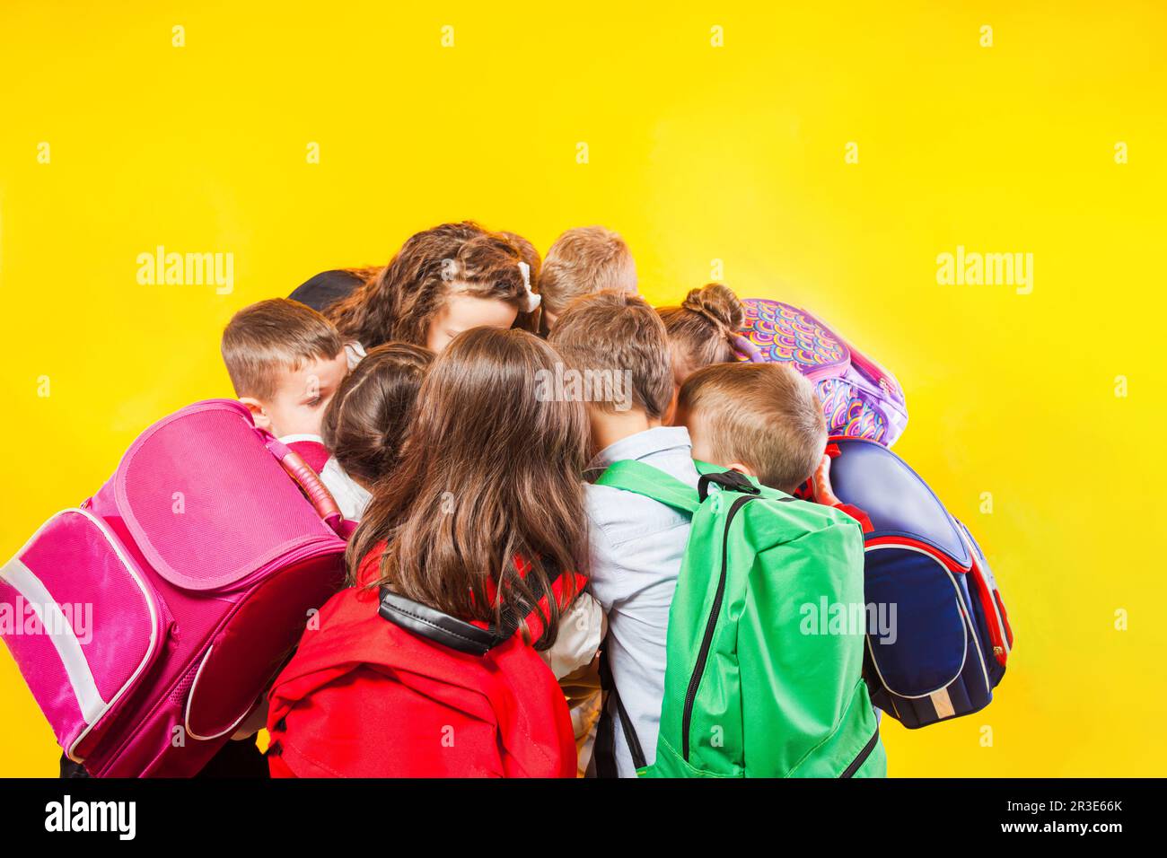 Gli scolari stanno accatastando le mani insieme sullo sfondo giallo Foto Stock