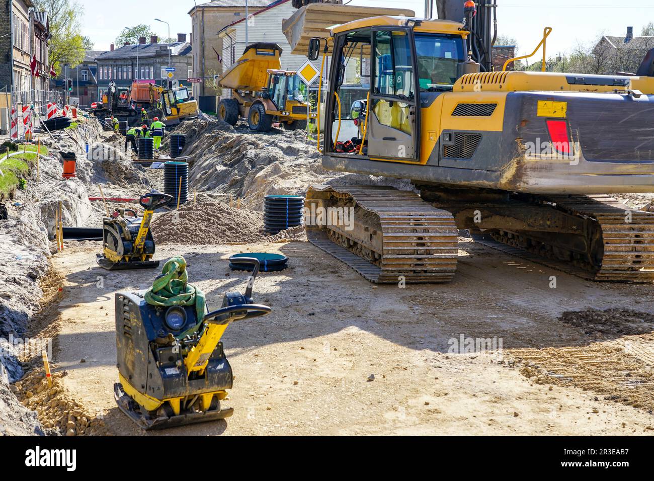 Vista del sito di ricostruzione stradale con lavoratori, diversi escavatori, compattatori a piastre vibranti e altri macchinari Foto Stock