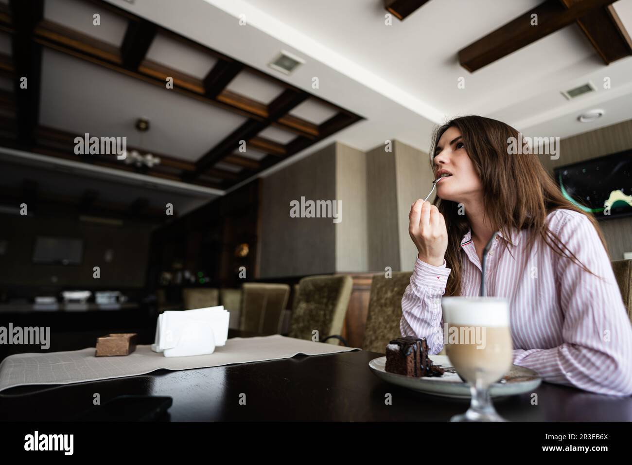 Giovane bella donna brunette sedersi al bar caffetteria ristorante interno. Foto Stock