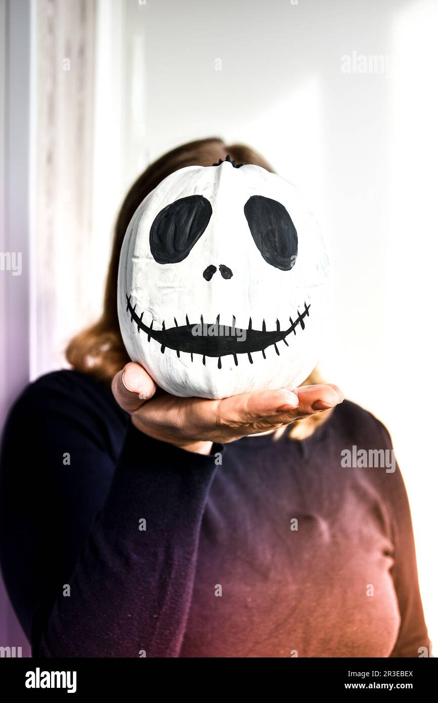 Donna che tiene la faccia di zucca divertente davanti alla sua faccia. Halloween sfondo Diy. Fai da te. Foto Stock