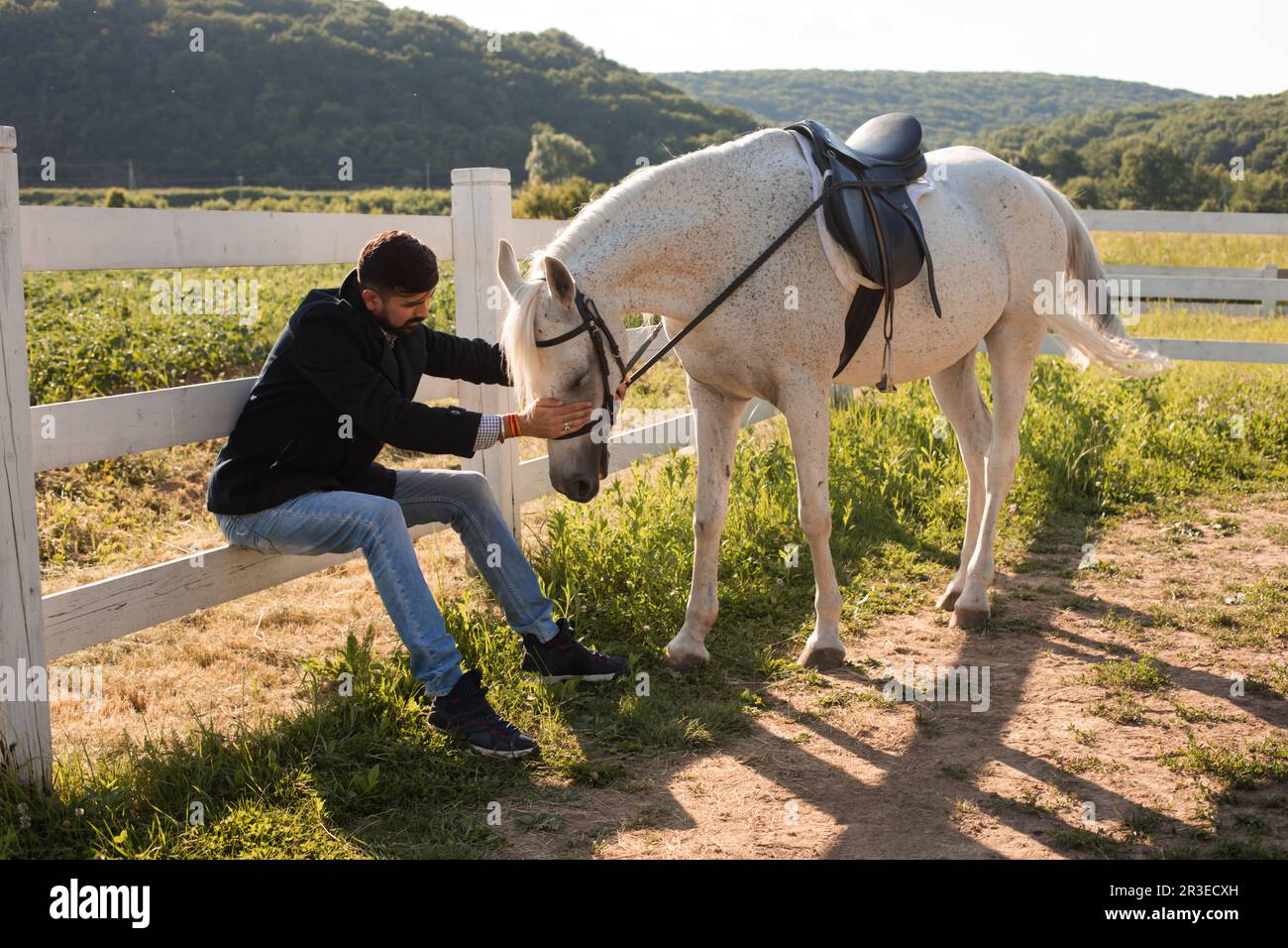 L'uomo riposa con un cavallo su un ranch Foto Stock