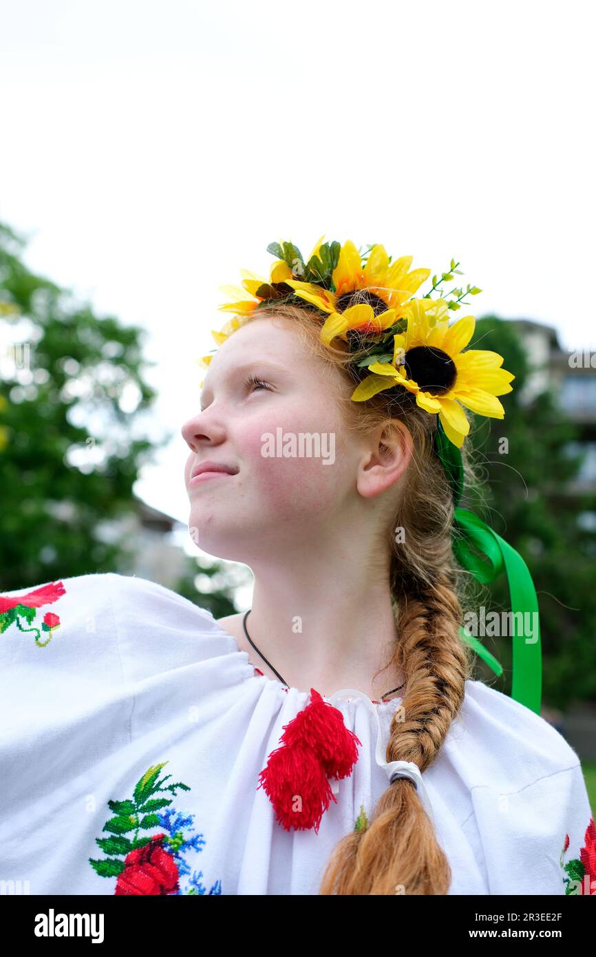 Ragazza soleggiato con capelli rossi luminosi si trova sullo sfondo di alberi verdi con corona di girasoli ricamati camicia nazionale donna Ucraina per la pace No guerra vittoria del patriottismo nazionale Ucraina Foto Stock