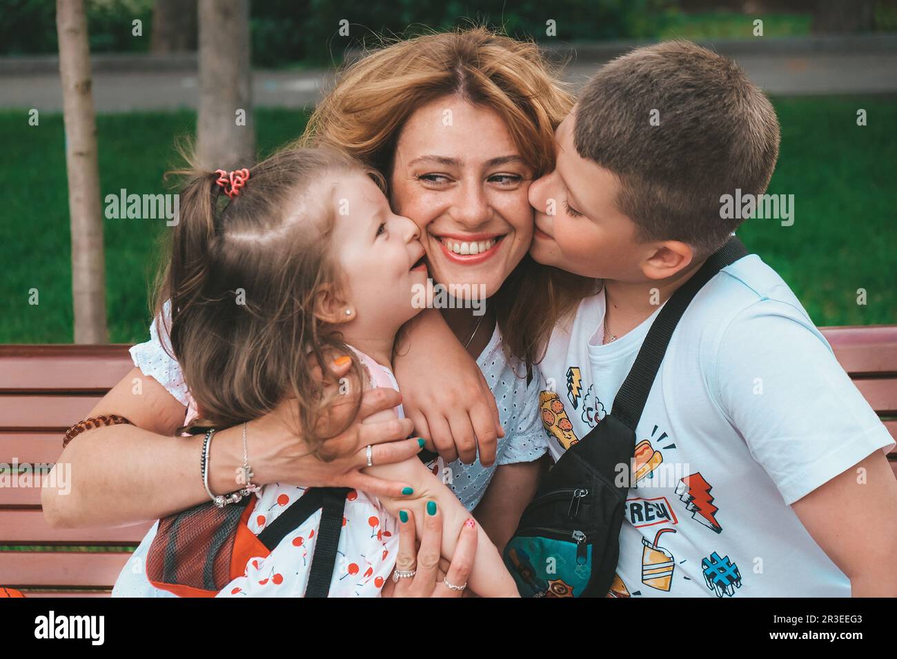 Ritratto di famiglia. Madre con figlia e figlio fuori nel parco. I bambini baciano la loro mamma. Amore per la famiglia Foto Stock