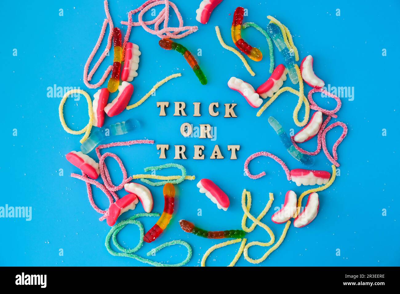 Concetto di Halloween. Decorazioni per feste di Halloween con parole TRICK O TREAT, dolci, vista dall'alto piatto su sfondo blu Foto Stock