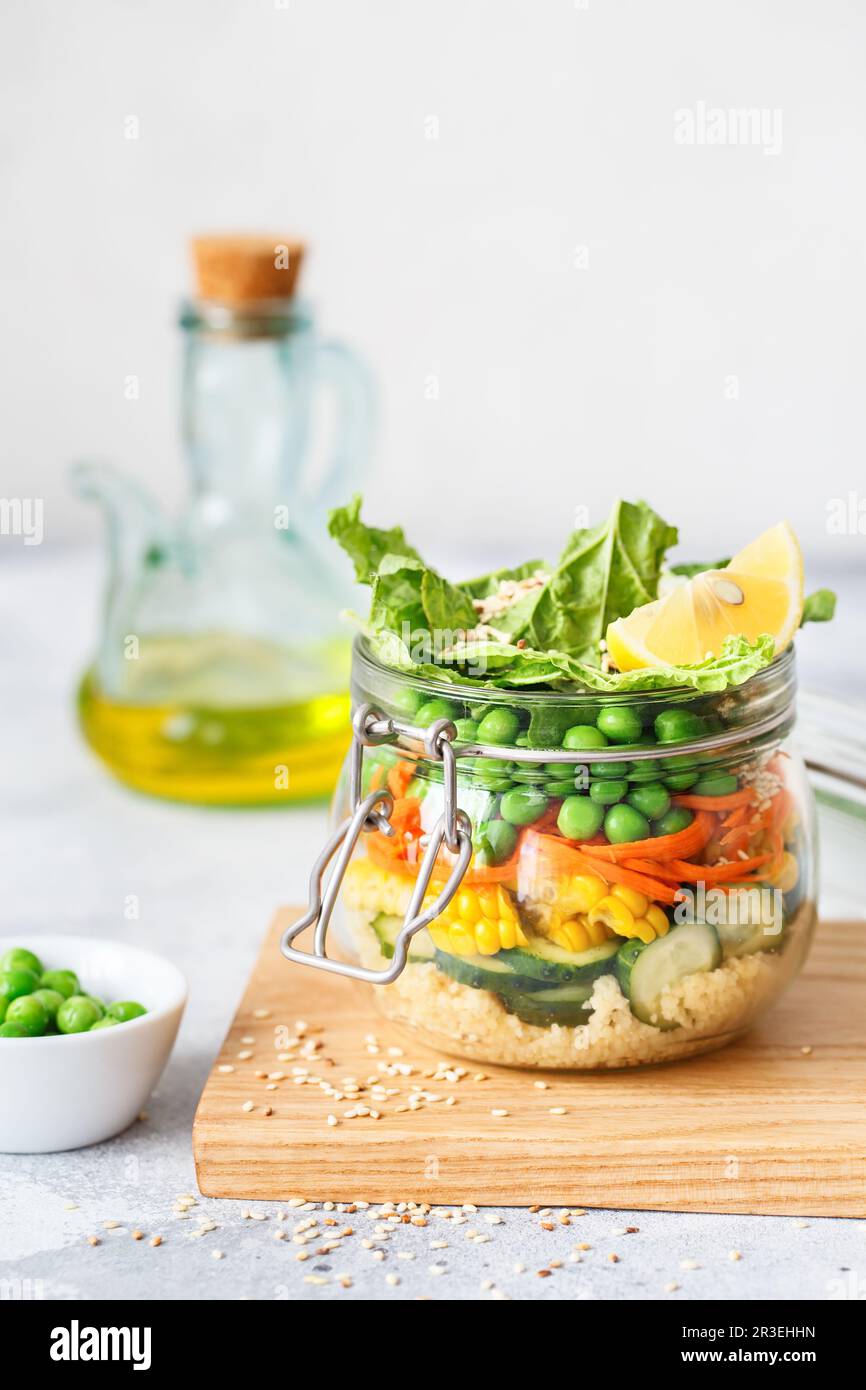 Vaso di vetro con verdure fresche crude e cuscus. Preparazione dei pasti sani - foto di preparazione delle ricette. Piatti vegani sani in Foto Stock