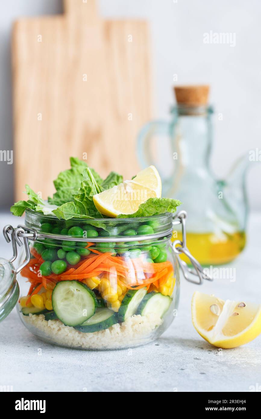 Vaso di vetro con verdure fresche crude e cuscus. Preparazione dei pasti sani - foto di preparazione delle ricette. Piatti vegani sani in Foto Stock