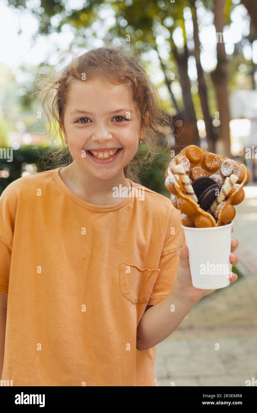 La bambina sta gustando un waffle belga Foto Stock