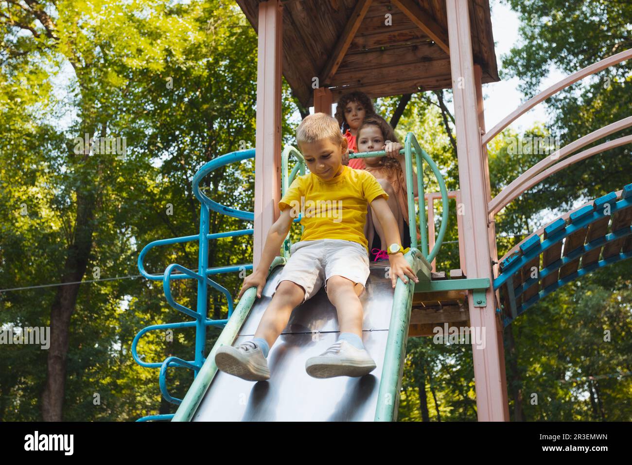 I bambini felici che si divertono a scivolare nel parco giochi Foto Stock