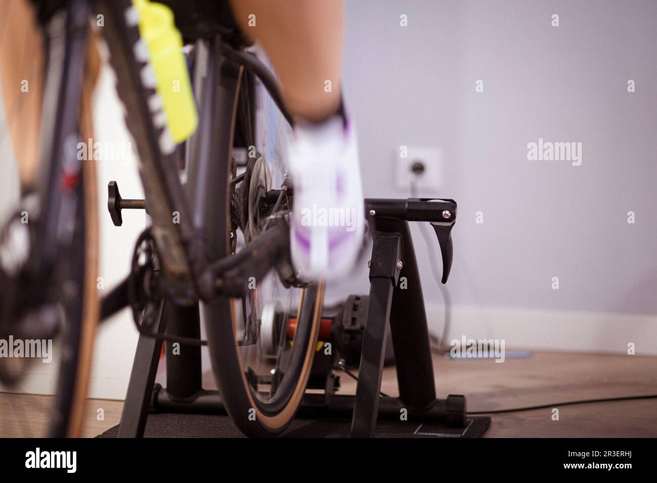 Due gambe pedalando una bicicletta in un allenatore al coperto in una casa domestica sport indoor tempo libero Foto Stock