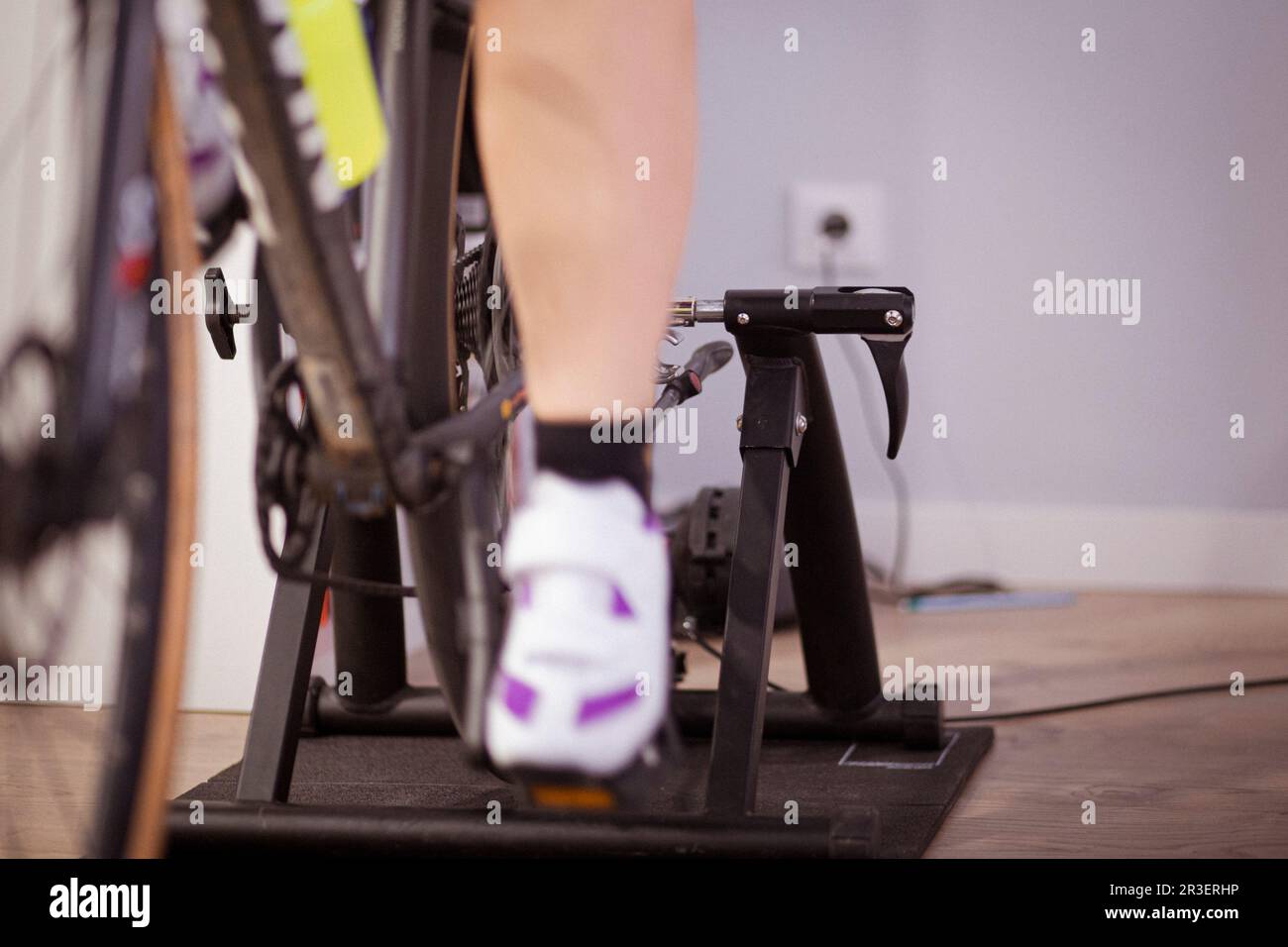 Due gambe pedalando una bicicletta in un allenatore al coperto in una casa domestica sport indoor tempo libero Foto Stock