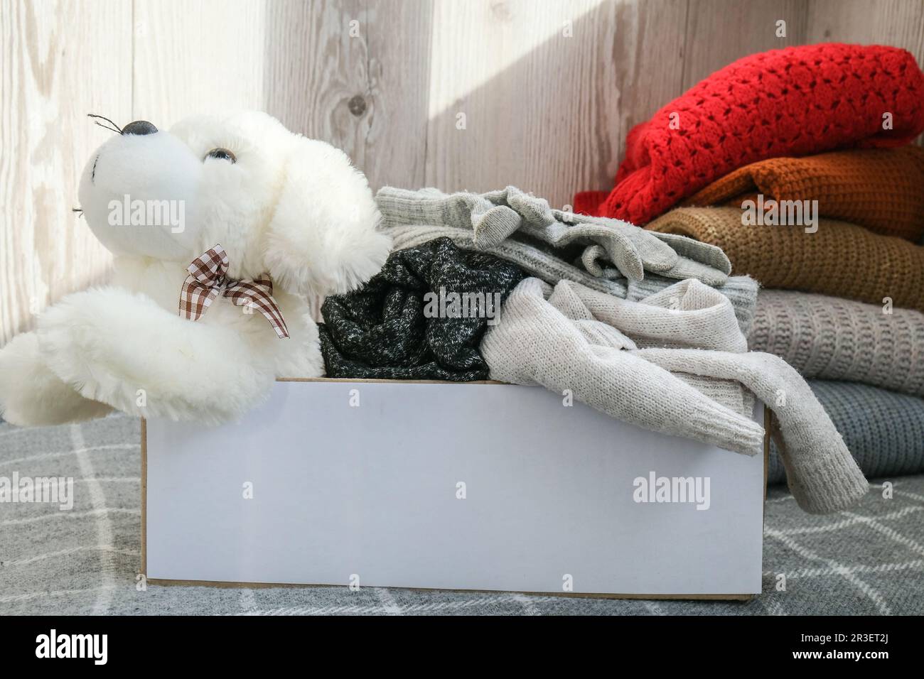 Scatola per donazioni con giocattoli e abiti usati in ambienti chiusi. Buona carità. Scatola con i vestiti in esso. primo piano. Donazione di abbigliamento. Inverno Foto Stock