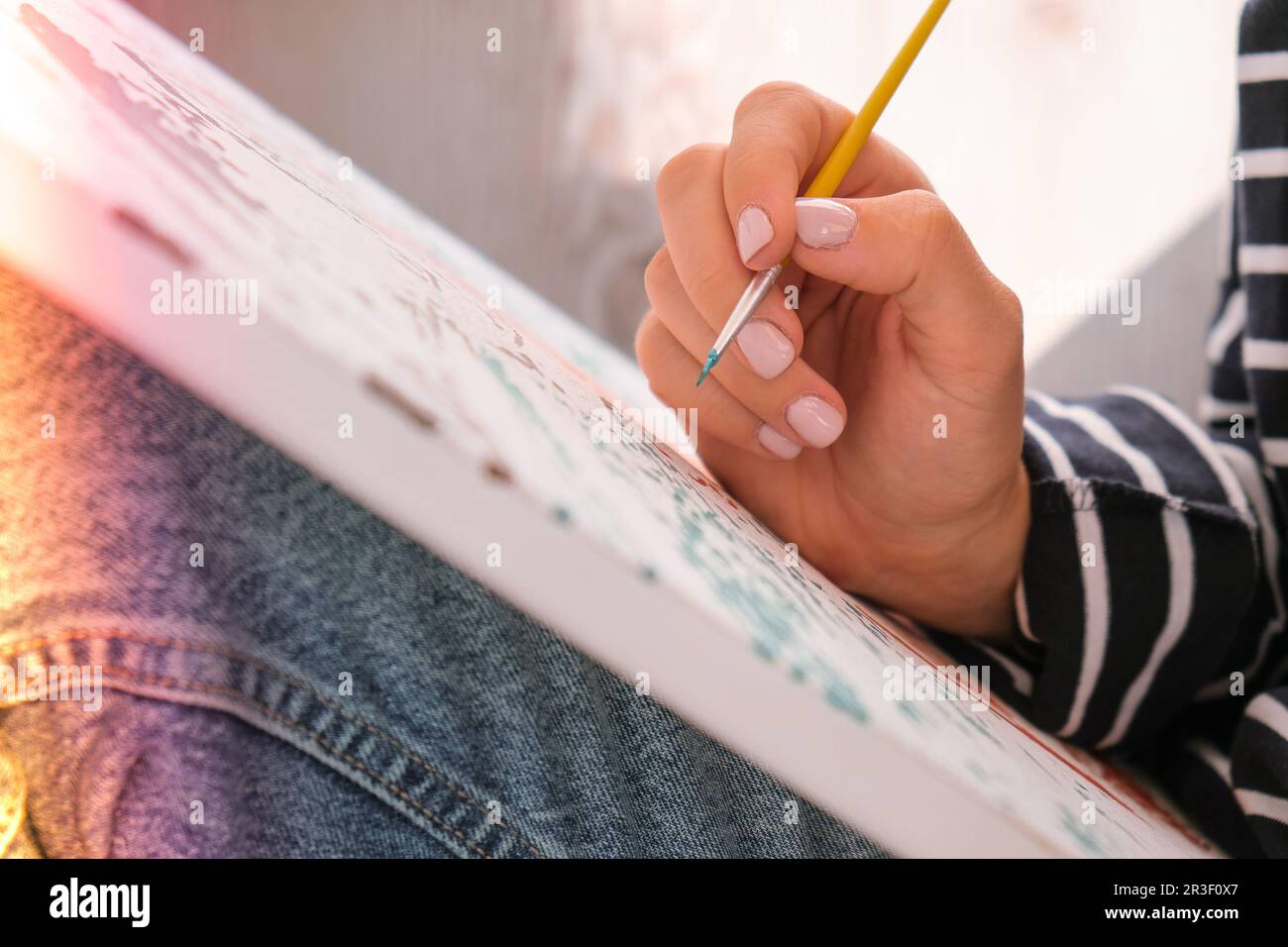 Pittura su tela con numeri e vasi di vernice numerati. Donna disegna con un pennello. Hobby creativo. Pittura per principianti. Leis Foto Stock