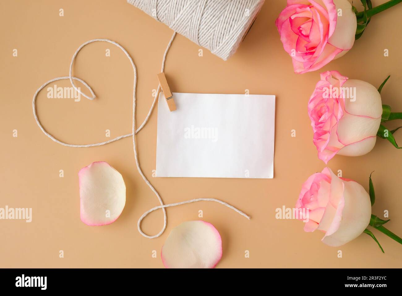Rosa rosa tenue con rocchetto di corda di cotone bianco a forma di cuore su fondo beige. Vuoto carta nota copia spazio minimo trendy Foto Stock